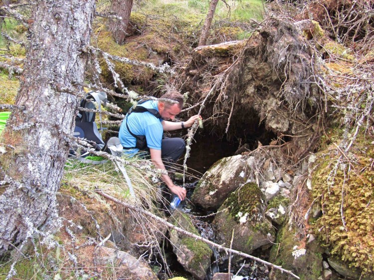 Refilling water bottles in Glen Affric